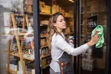 Woman cleaning front door of retail store