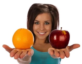 woman holding out orange and apple