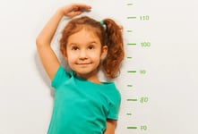 child measuring her height against wall
