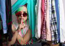 Girl with a secret peeking out from clothing rack