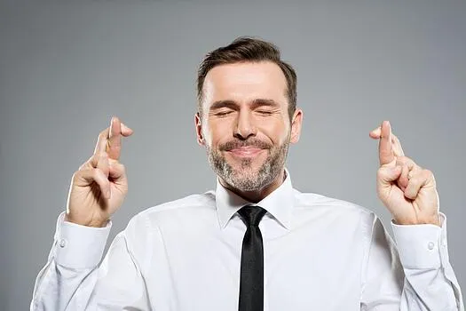 Man with eyes closed and fingers crossed