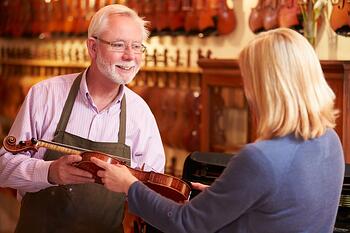 Salesman showing violin to customer